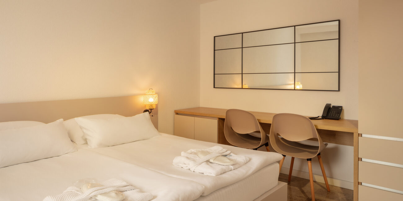 A warm, bright bedroom at the SeeSea Hotel in Vodice, Croatia, featuring a luxurious king-size bed and a comfortable writing desk. Perfect for a relaxing stay in the Family Suite.