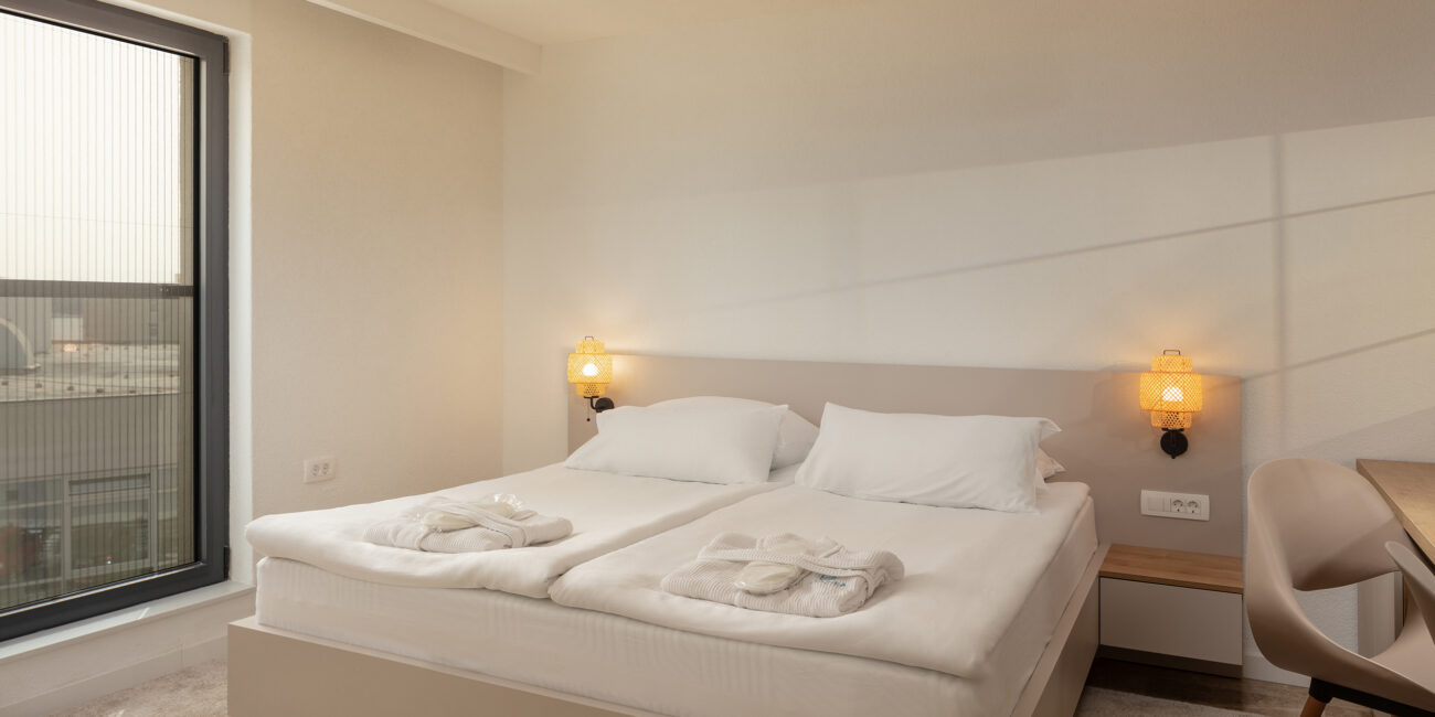 Inviting and cozy bedroom in the Family Suite at SeeSea Hotel, Vodice, Croatia, with a spacious king-size bed and a well-lit writing desk, ideal for both rest and work.