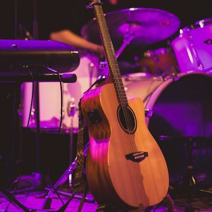 Close-up of a guitar on stage with a drummer in the background during a live performance.